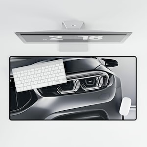May include: A black and silver car with a white keyboard on top of it. The car's headlights are on and the keyboard is a standard computer keyboard.