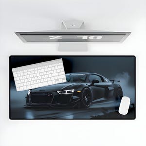 May include: A black car with a white stripe on the front, a white keyboard, and a white mouse on a black desk mat with a dark blue background.