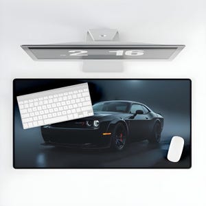 May include: Black mouse pad featuring a black sports car with red brake calipers. A white keyboard and mouse are on the pad. A computer monitor is above the pad.