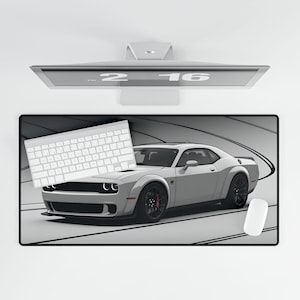 May include: A white Dodge Challenger Hellcat sits on a gray and black racing track themed mousepad. A white keyboard and a white mouse are also on the mousepad.