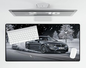 May include: A black and white desk mat with a black car driving on a snowy road. The car has a license plate that reads "M.M 5022". A white keyboard and a white mouse are on the mat.