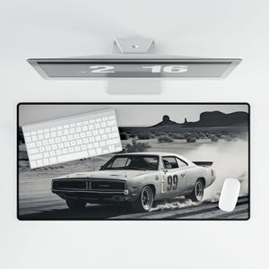 May include: A black and white photo of a white Dodge Charger with the number 99 on the side, driving on a dirt road with smoke coming from the tires. The car is in focus, while the background is blurred.