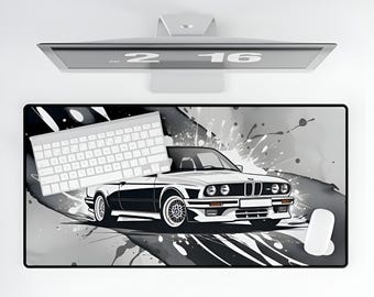 May include: A black and white mousepad with a black and white image of a car and paint splatters. The car is a white BMW with black accents. A white keyboard is on the left side of the mousepad.