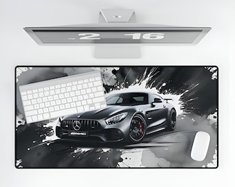 Puede incluir: Un ratón de ordenador negro y blanco con un coche deportivo negro y salpicaduras de pintura blanca. El coche es un Mercedes-Benz AMG GT con el logotipo de AMG en la parte delantera. El ratón también tiene un teclado blanco y un ratón blanco.