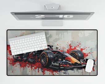 May include: A rectangular mouse pad featuring a Red Bull Formula 1 race car design with red paint splatter on a gray background. A white keyboard and mouse are on the pad, with a computer monitor above.