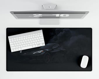 Peut inclure: Tapis de souris rectangulaire noir avec un design de voiture de sport noire aux accents rouges, sur fond sombre et enfumé. Un clavier et une souris blancs sont positionnés sur le tapis. Un écran d'ordinateur est au-dessus.