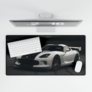 May include: A black and white mouse pad with a white Dodge Viper sports car on a black background. A white keyboard is on the left side of the mouse pad.