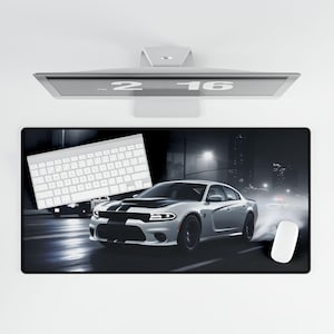 May include: A black and white computer mouse pad with a white keyboard and a white Dodge Charger on a dark city street at night. The car has a black stripe on the hood and black wheels.