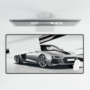 May include: A white keyboard and a white mouse are on a black and white desk mat with a silver sports car in the background. The desk mat has a black and white abstract design.