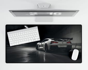 Peut inclure: Un tapis de souris noir et blanc avec une voiture de sport blanche sur un fond sombre. La voiture a des feux arrière rouges et un clavier blanc est sur le côté gauche du tapis de souris.