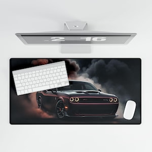 May include: Black rectangular desk mat featuring a maroon sports car with smoke effects. A white keyboard and mouse are on the mat. A computer monitor displays the numbers "2 16".