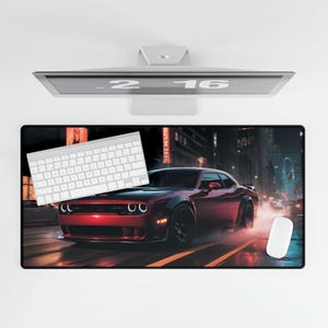 May include: A red Dodge Challenger muscle car driving through a city at night. The car has black accents and black wheels. The car is driving on a wet road with a white keyboard and a white mouse on the surface.