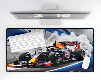 May include: A black and red Formula One race car with the words "Red Bull" on the side, driving on a blue and white race track with smoke coming from the tires. The car is on a black and blue mouse pad with a white keyboard in the background.