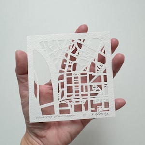 May include: White paper cut-out art of the University of Minnesota campus, with the text "university of minnesota // K. Kolbany" at the bottom.