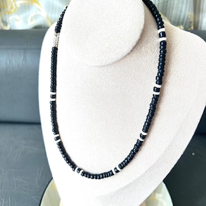 May include: A black and white beaded necklace with a silver clasp. The necklace is made of small, round beads and is approximately 18 inches long.