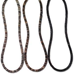May include: Three necklaces made of brown, black, and white shell beads. The necklaces are all the same length and have a magnetic clasp.