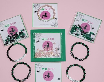 Può includere: Una collezione di braccialetti di perline e materiali per l'artigianato a tema Halloween. I braccialetti presentano perline nere e verdi che compongono parole come "Wicked" e nomi. La confezione include biglietti con una grafica di strega e la parola "Wicked".