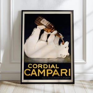 May include: Framed vintage advertisement poster for Cordial Campari. The poster features a white polar bear pouring a bottle of Campari into its mouth. The text "Cordial Campari" is in gold lettering on a black background.