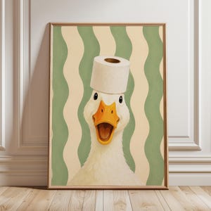 Pode incluir: Uma impressão de arte de parede emoldurada apresentando um pato branco com bico laranja e boca aberta, usando um rolo de papel higiênico branco na cabeça. O fundo consiste em listras verticais onduladas em tons de verde sálvia e creme.