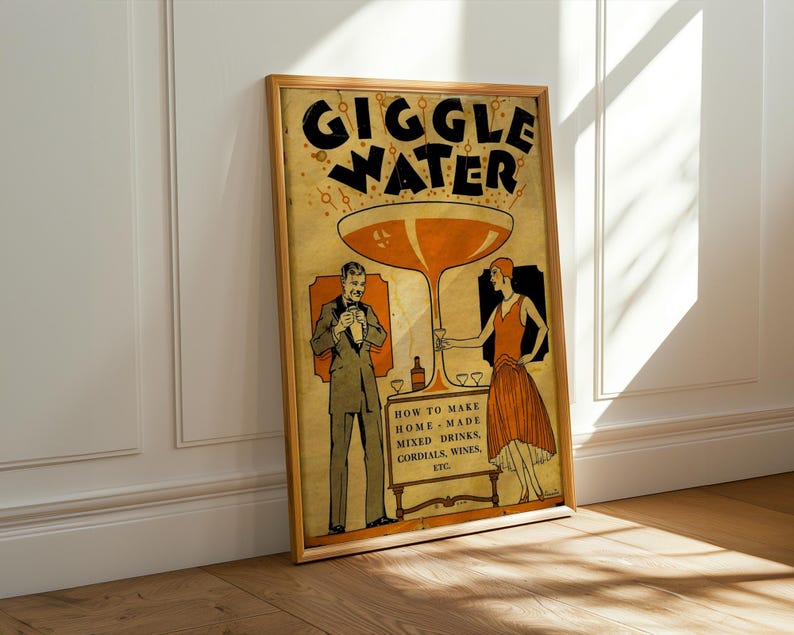Op de afbeelding: Een ingelijste poster in vintage-stijl met de woorden "GIGGLE WATER" in grote zwarte letters. De poster bevat illustraties van een man en een vrouw, en de tekst "HOW TO MAKE HOME MADE MIXED DRINKS, CORDIALS, WINES, ETC."