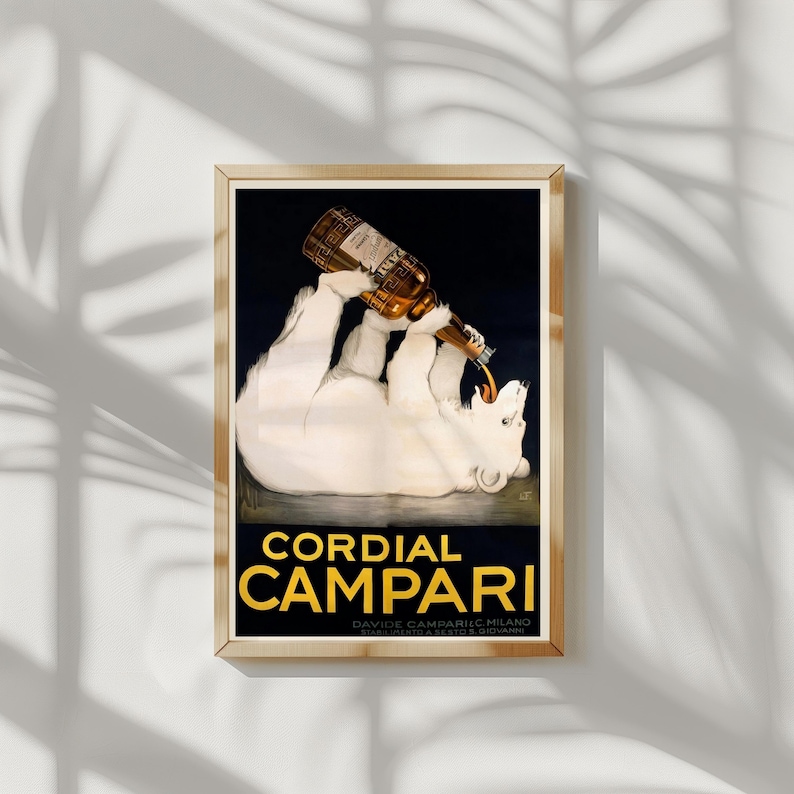 Pu&ograve; includere: Una pubblicit&agrave; vintage incorniciata per Cordial Campari. L'opera presenta un orso polare bianco che beve da una bottiglia di Campari. Il testo "Cordial Campari" &egrave; in lettere dorate.
