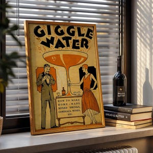 Op de afbeelding: Een ingelijste vintage poster met de woorden "GIGGLE WATER" in grote zwarte letters. De poster toont een stel in kleding uit de jaren 1920, met instructies voor het maken van mixdrankjes. Een fles wijn en opgestapelde boeken staan op een vensterbank.