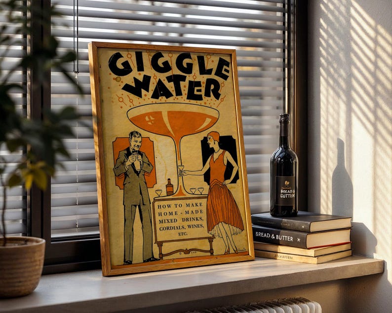 Op de afbeelding: Een ingelijste vintage poster met de woorden "GIGGLE WATER" in grote zwarte letters. De poster toont een stel in kleding uit de jaren 1920, met instructies voor het maken van mixdrankjes. Een fles wijn en opgestapelde boeken staan op een vensterbank.