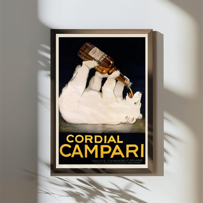 Pu&ograve; includere: Una pubblicit&agrave; vintage incorniciata per Cordial Campari. L'opera presenta un orso polare bianco che tiene in mano una bottiglia di Campari, con la bevanda che si versa nella sua bocca. Il testo "Cordial Campari" &egrave; in lettere gialle.