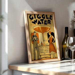 Op de afbeelding: Een ingelijste vintage print met de woorden "GIGGLE WATER". Het kunstwerk toont een groot cocktailglas en figuren in historische kleding. De print bevat ook tekst over het maken van mixdranken. Een fles en een wijnglas staan ernaast.