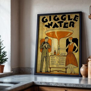 Op de afbeelding: Een ingelijste vintage poster met de woorden "GIGGLE WATER" in grote letters. De poster bevat illustraties van een man en een vrouw, een groot cocktailglas en de tekst "HOW TO MAKE HOME-MADE MIXED DRINKS, CORDIALS, WINES, ETC."