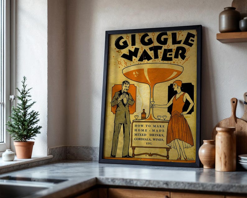 Op de afbeelding: Een ingelijste vintage poster met de woorden "GIGGLE WATER" in grote letters. De poster bevat illustraties van een man en een vrouw, een groot cocktailglas en de tekst "HOW TO MAKE HOME-MADE MIXED DRINKS, CORDIALS, WINES, ETC."