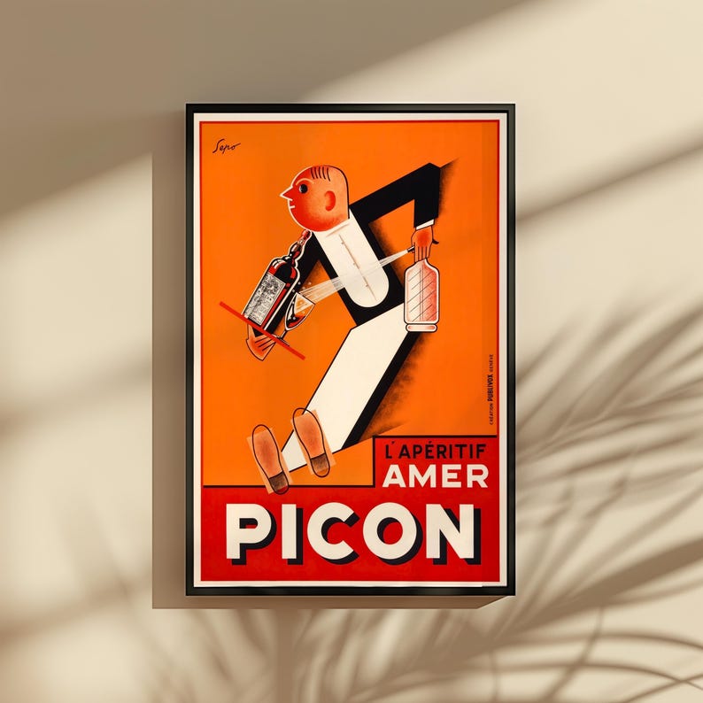 May include: Framed vintage advertisement poster for Picon, featuring a stylized figure in a tuxedo carrying bottles. The poster has a vibrant orange background with the text "L'APERITIF AMER PICON" in red and white.