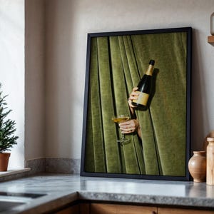 May include: A framed wall art print featuring a dark green velvet curtain backdrop. A bottle of champagne and a filled coupe glass are held through the fabric folds. The composition highlights the contrast between the deep green textile and the glass.