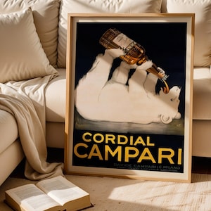 Pu&ograve; includere: Un poster vintage incorniciato per Cordial Campari. L'opera presenta un orso polare bianco che beve da una bottiglia di Campari. Il testo "CORDIAL CAMPARI" &egrave; in lettere dorate su sfondo nero. Il poster &egrave; in una cornice di legno.