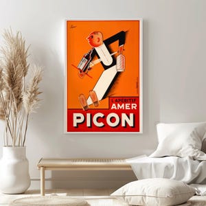 May include: Framed vintage advertisement poster for Picon, an aperitif. The artwork features a stylized figure in a tuxedo carrying bottles against an orange background. The poster has the text "L'APERITIF AMER PICON" in red and white.