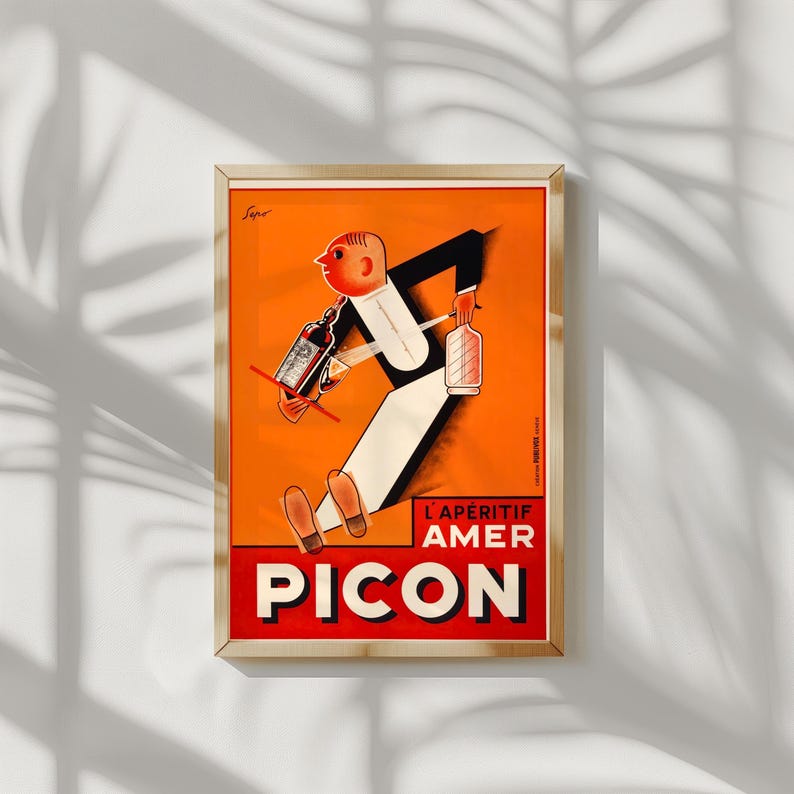 May include: Framed vintage advertisement poster for Picon Amer, featuring a stylized figure carrying bottles against an orange background. The poster has a red and white banner with the word "PICON".