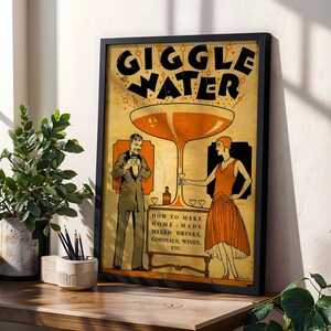 Op de afbeelding: Een ingelijste poster in vintage-stijl met de woorden "GIGGLE WATER" in grote zwarte letters. De poster bevat illustraties van een man en een vrouw in vintage kleding, met de tekst "HOW TO MAKE HOME-MADE MIXED DRINKS, CORDIALS, WINES, ETC."