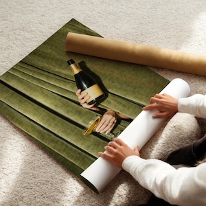 May include: A rectangular wall art print featuring a dark olive green velvet curtain backdrop with a centered photographic cutout showing a champagne bottle and a glass. The print is displayed on a white surface with a brown cardboard shipping tube.