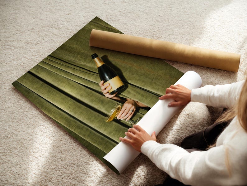 May include: A rectangular wall art print featuring a dark olive green velvet curtain backdrop with a centered photographic cutout showing a champagne bottle and a glass. The print is displayed on a white surface with a brown cardboard shipping tube.