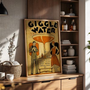 Op de afbeelding: Een ingelijste vintage poster met de woorden "GIGGLE WATER" in grote letters. De poster toont illustraties van een man en een vrouw, een groot cocktailglas en de tekst "HOW TO MAKE HOME MADE MIXED DRINKS, CORDIALS, WINES, ETC."