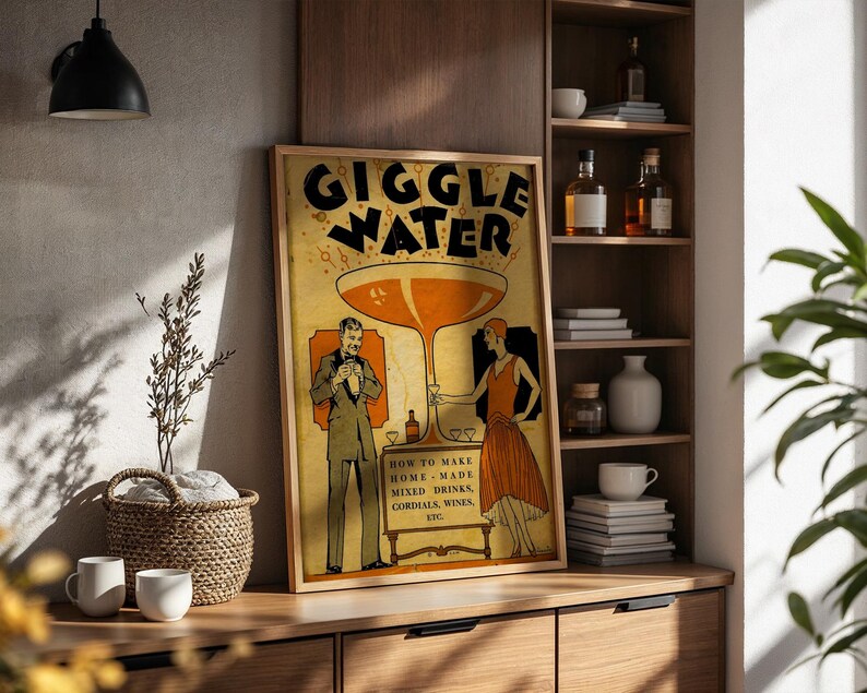Op de afbeelding: Een ingelijste vintage poster met de woorden "GIGGLE WATER" in grote letters. De poster toont illustraties van een man en een vrouw, een groot cocktailglas en de tekst "HOW TO MAKE HOME MADE MIXED DRINKS, CORDIALS, WINES, ETC."