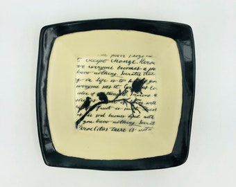 Handmade ceramic plate with antique looking cursive writing behind a row of birds sitting on a branch