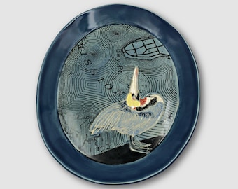 Ceramic wall platter with a background topo map of Mission Bay and a sgraffito carved Pelican in Breeding Plumage Artistic gift for a birder