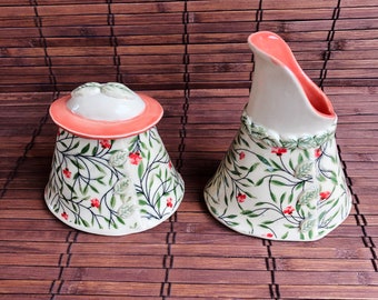 Handmade ceramic sugar bowl and cream pitcher in retro calico floral pattern, in cream and salmon colored glazes.