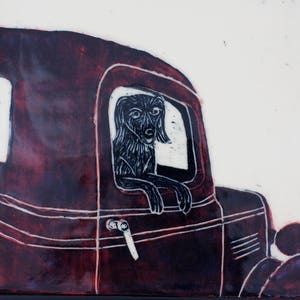 May include: A dark red vintage car with a black and white illustration of a dog looking out the window. The dog's head and paws are visible, giving the impression of a pet enjoying a car ride. The artwork is on a white background.