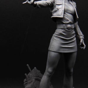 May include: A monochromatic gray anime-style figurine of a character with shoulder-length hair, wearing a collared jacket, a fitted top, a skirt with a belt, and boots. The figure stands in a dynamic pose with one arm extended forward.
