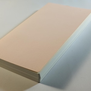 May include: A stack of blank, pale pink paper with white edges.