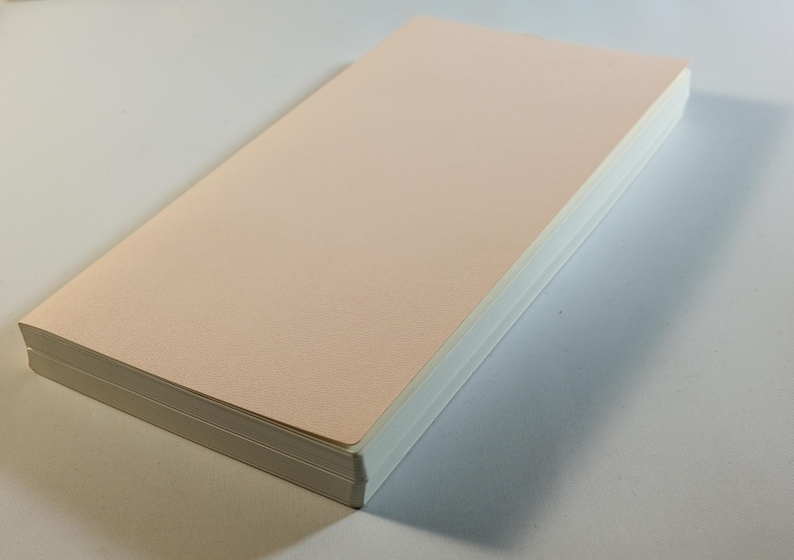 May include: A stack of blank, pale pink paper with white edges.