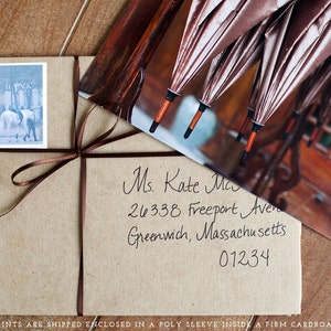Op de afbeelding: Een bruine papieren envelop met een wit label waarop "LEFT BYNK" staat en een handgeschreven adres aan Ms. Kate Ma, 26338 Freeport Avenue, Greenwich, Massachusetts 01234. De envelop is vastgebonden met een bruin lint.