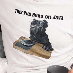 May include: White t-shirt featuring a black dog with a coffee cup on a wooden tray. The text "This Pup Runs on Java" is printed above the dog. The dog has a serious expression.
